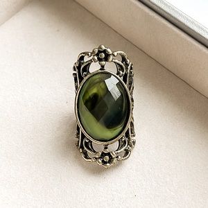 Fun ring with gold ornate band design and green gemstone.